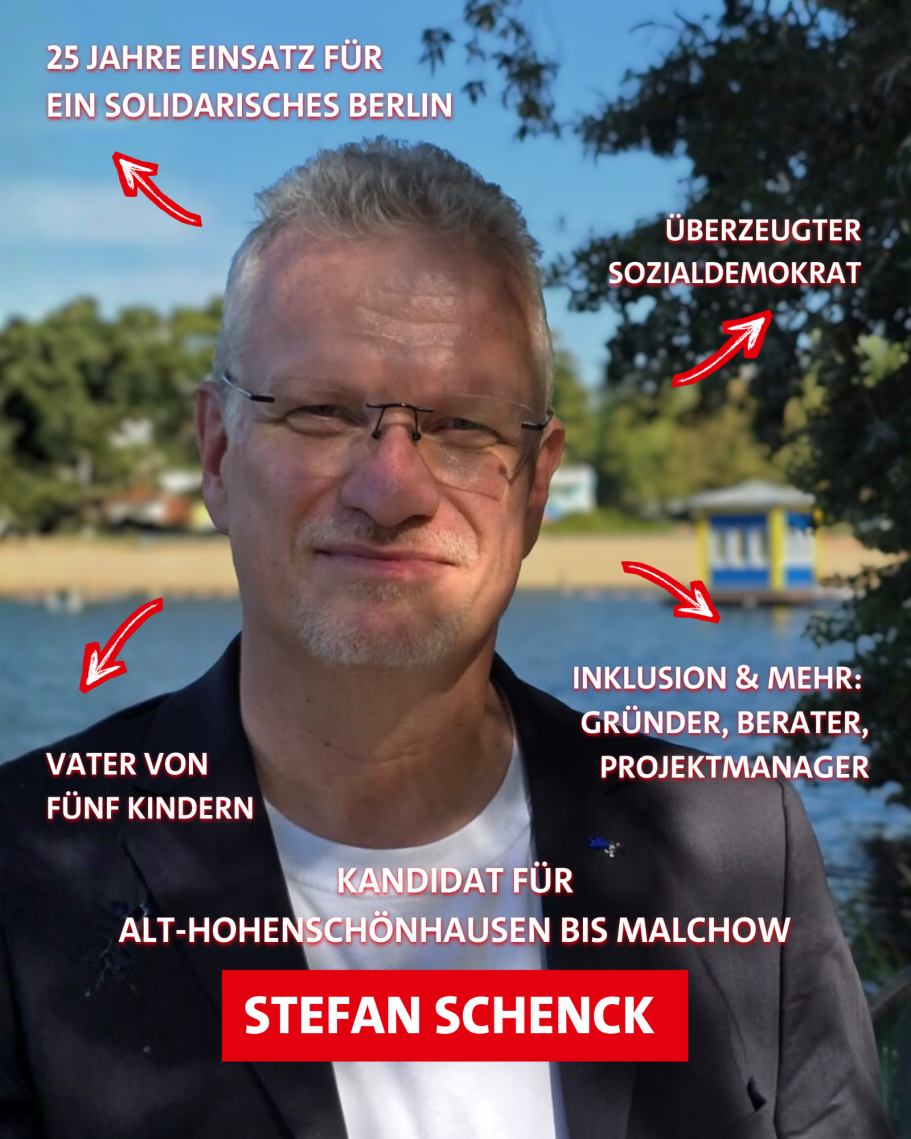 Mann mit Brille schaut in die Kamera. Hinter ihm sind ein See, ein Strand, Bäume und blauer Himmel zu sehen.